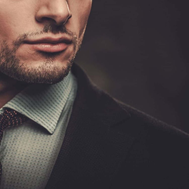 Close-up of the lower half of a man's face, showcasing a well-groomed beard and mustache that exhibit masculine qualities. He